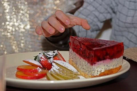 Hand hovering over the plate with cake and fruit Stock Photos