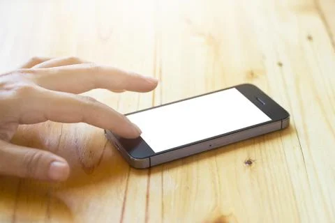 Hand husing smartphone with blank screen on wooden table 스톡 사진