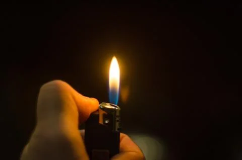 Hand Igniting Cigarette Lighter Isolated On Black Background Foto stock