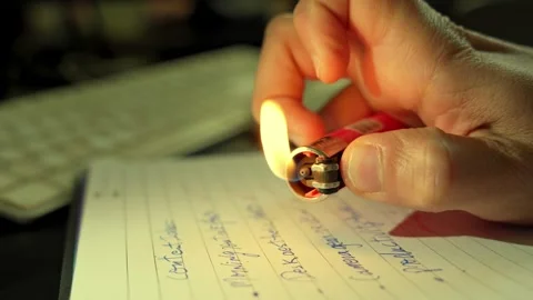 Hand Igniting Lighter Over Notebook in Dramatic Close-Up Video stock 312739649