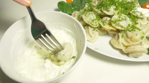 A hand impales meet dumpling with a fork   and dips in a sour cream Stock Footage 63780659