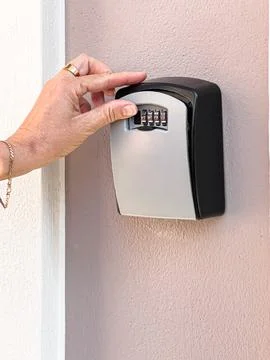 Hand inputting code on key lockbox for access 스톡 사진