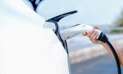 Hand insert EV charger plug into electric vehicle to recharge EV car. Perpetual Foto stock