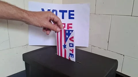 Hand inserting american flag ballot paper into black box Stock Footage 341701354