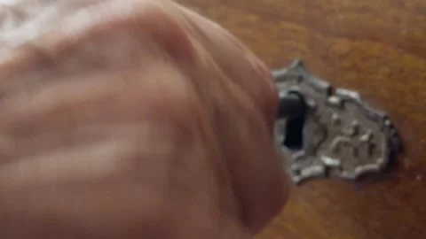 Hand Inserting Antique Key Into Vintage Lock Keyhole On Wooden Drawer Close-Up Stock Footage 346764896