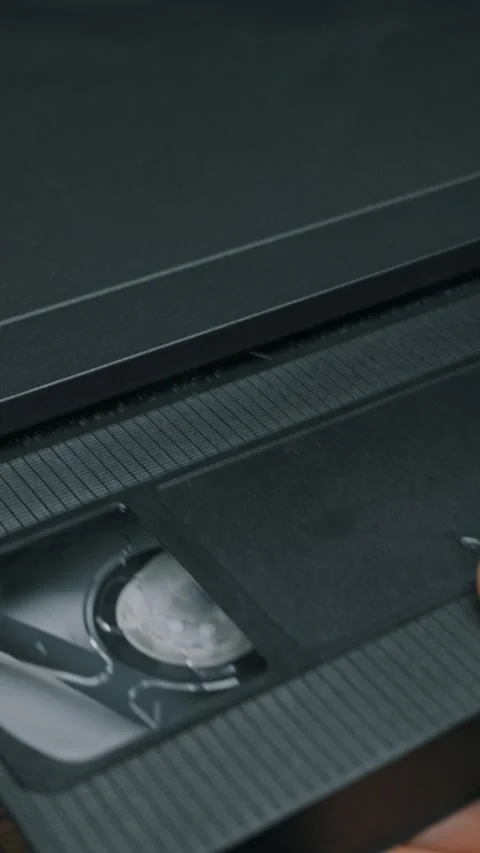 Hand Inserting Black VHS Cassette Tape Into Vintage VCR Player Vídeos de archivo 329968037