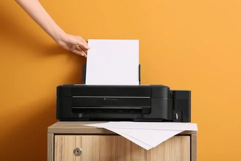 Hand inserting blank paper into black inkjet printer for document printing an Stock Photos