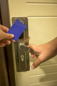 A hand inserting a blue card key into a modern hotel door lock, key electroni Stock Photos
