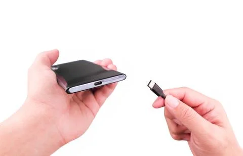Hand inserting the charging cable into the Type C port of a smartphone. 스톡 사진