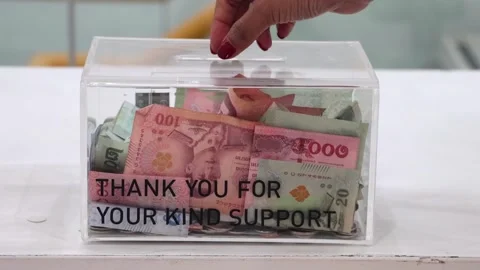 A hand is inserting a coin into the donation box Stock Footage 314062132