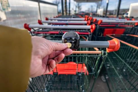 Hand inserting coin or token into Super U shopping cart lock in Dijon 库存照片