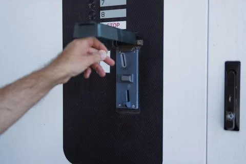 Hand inserting a coin into a payment slot on an automatic machine, initiati.. Stock Photos