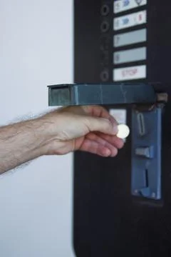 Hand inserting coin into a vending machine, illustrating payment for a serv.. Stock Photos
