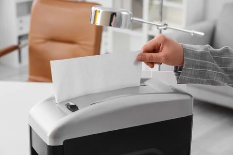 Hand inserting confidential document into paper shredder for data protection  Stock Photos