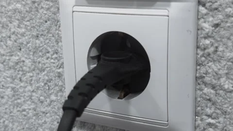 Hand inserting electrical plug into wall socket power outlet and and stick out. Stock Footage 344844848