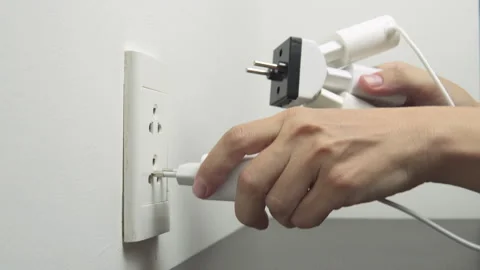 Hand inserting electrical plugs into outlet. Electrical overload Stock Footage 314776130