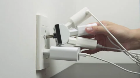 Hand inserting electrical plugs into outlet. Electrical overload Stock Footage 326614498