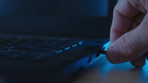 Hand inserting flash drive or thumb drive into laptop computer in dark office Stock Footage 334734202