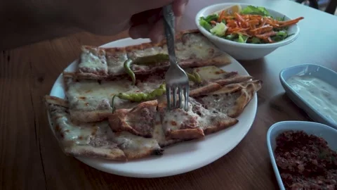 A hand inserting a fork into hot minced meat and melted cheese Turkish pide 库存影片 341104295