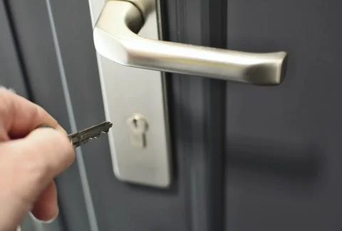 A Hand is inserting a key into the door lock. 库存照片