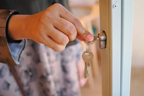 Hand inserting key into door lock at home Stock Photos
