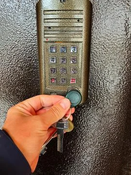 Hand inserting key fob into a security keypad system Stock Photos