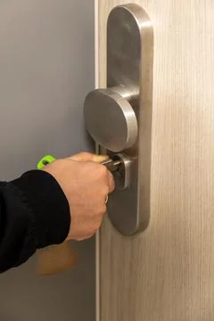 Hand inserting key into modern door lock Stock Photos