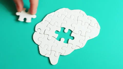 Hand Inserting Missing Puzzle Piece into Brain Shape on Teal Surface Stock Footage 295112122