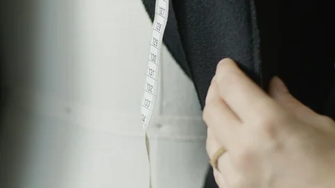 Hand inserting needle in black fabric with measuring tape in background Vídeos de archivo 124244227