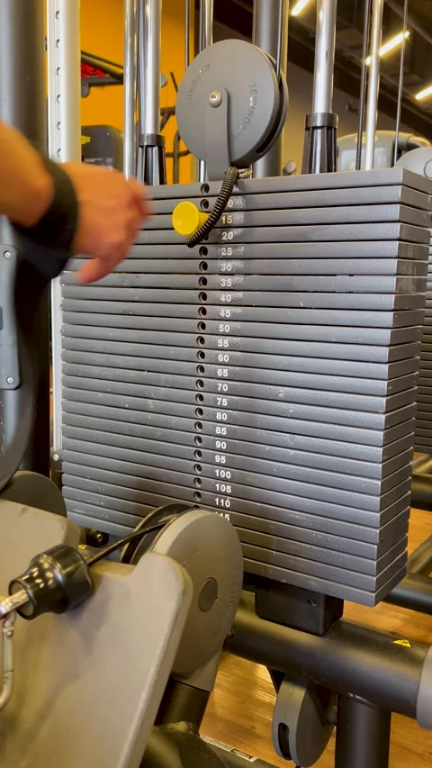 Hand inserting pin in weight stack machine - gym load selection training Stock Footage 337380600
