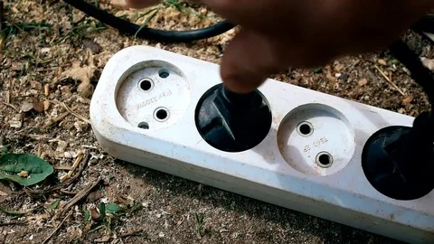 Hand inserting a plug into socket outdoors Stock Footage 74750816