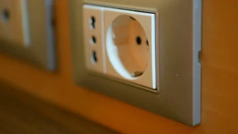 Hand inserting a plug in the socket on the wall closeup Stock Footage 89700464