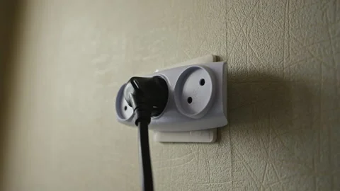 Hand inserting power plug into wall socket, establishing electrical connection Stock Footage 310799730