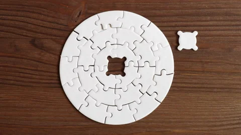 Hand Inserting Puzzle Piece into Circular Design on Wooden Surface Stock Footage 295112930