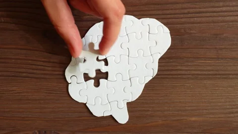 Hand Inserting Puzzle Pieces into Brain Shape on Wooden Background Stock Footage 295112600