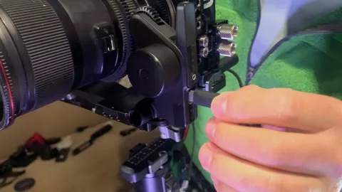 Hand inserting USB-C cable into camera stabilizer for manual focus control Stock Footage 333649546