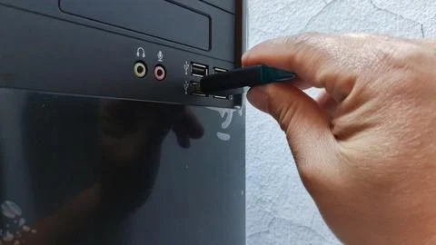 Hand inserting a USB drive into a computer port Stock Photos