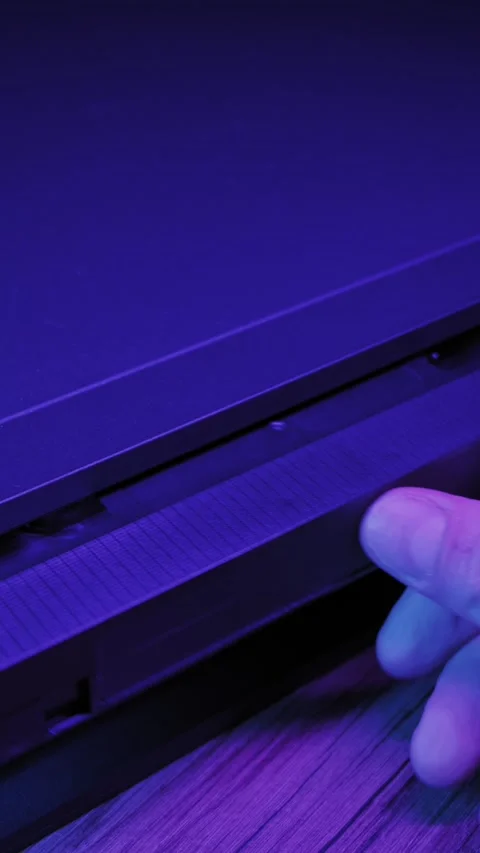 Hand Inserting Vintage VHS Tape Into Player Under Purple Neon Light Video stock 330273061