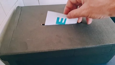 Hand inserting voting ballot into dark cardboard box motion footage clip Stock Footage 341626249