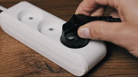 Hand Inserts Black Grounded Plug into Outlet Side View 動画素材 320353949