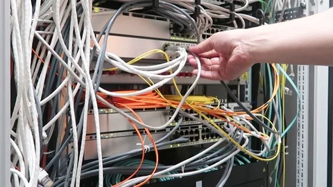 Hand inserts the cable into internet hub. IT engineer working in a data center Stock Footage 90000212