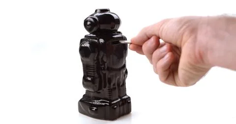 A hand inserts a coin into a glossy retro robot piggy bank Stock Photos
