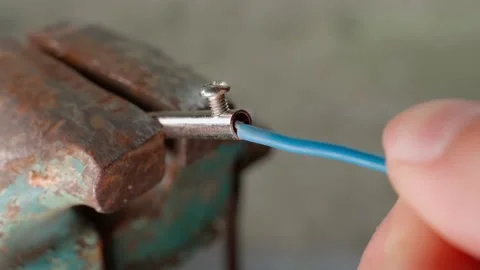 The hand inserts a copper wire in a blue braid inserts into the contact of the Stock Footage 208841465