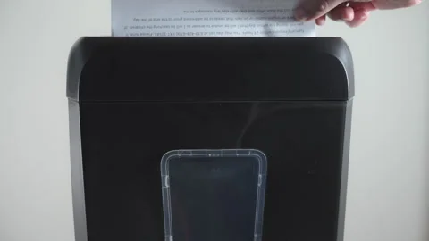 Hand inserts a document into a shredder for destruction Stock Footage 294157389