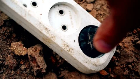 Hand inserts electric plug into socket outdoors Stock Footage 72902997