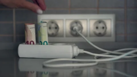 Hand inserts euro banknotes into electrical extension socket 스톡 동영상 234786174