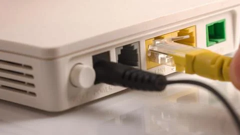Hand inserts Internet cable into computer router Stock Photos