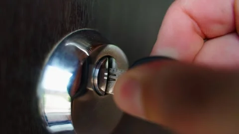 A hand inserts a key into a door lock, turns it and pulls it out close-up Stock Footage 270039401
