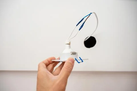 Hand inserts the lamp into the ceiling Stock Photos