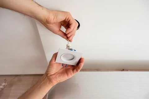 Hand inserts the lamp into the ceiling Stock Photos